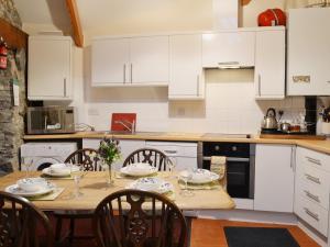 a kitchen with white cabinets and a wooden table with chairs at Gareth - 19077 in Carew