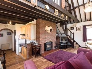 a living room with a fireplace and a brick wall at Sky Lark in Weybourne