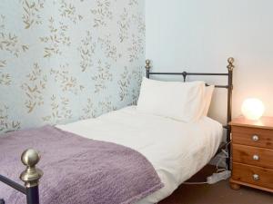 a bedroom with a bed with a pillow and a nightstand at Poppy Cottage in Bonsall