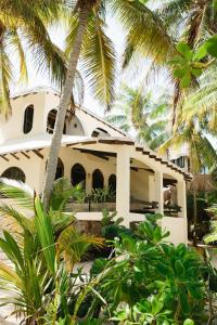 a white house with palm trees in front of it at Olas Tulum in Tulum