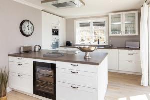 a kitchen with white cabinets and a clock on the wall at Beachalm in List