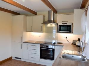 a kitchen with white cabinets and a sink at The Paddock in Saint Hilary