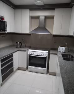 eine Küche mit weißen Schränken und einem Herd mit Backofen in der Unterkunft Mendoza is life in Guaymallen
