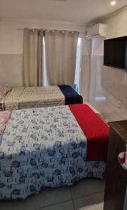 ブジオスにあるcasa com piscina e churrasqueira adoravelのベッドルーム1室(ベッド2台、薄型テレビ付)
