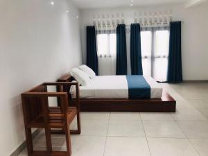 Le Majestic Toamasina Hotel في تاوماسينا: غرفة نوم بسرير والستائر الزرقاء وكرسي