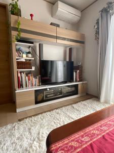 a living room with a flat screen tv in a entertainment center at B&B legare in Gifu