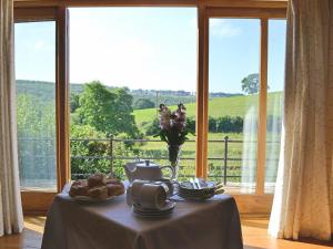 einen Tisch mit einer Vase Essen drauf mit einem Fenster in der Unterkunft Stockham Lodge in Colyton