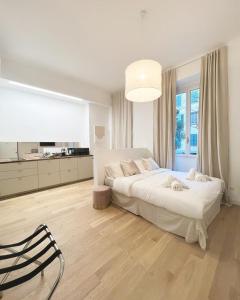 a white bedroom with a bed and a large window at Divini Gae Aulenti in Milan