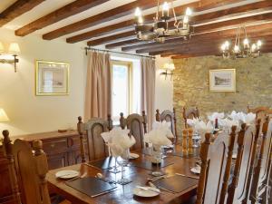 a dining room with a table and a stone wall at Stockham Lodge in Colyton