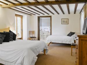 a bedroom with two beds and a tv in it at Stockham Lodge in Colyton