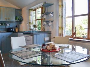 una cocina con una mesa de cristal con un plato de pavo en Mill Batch Cottage, en Mark