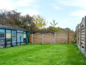 a wooden fence in a yard with green grass at Mill Batch Cottage in Mark