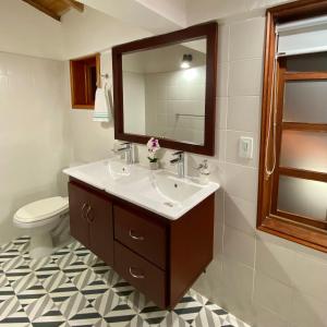 a bathroom with a sink and a mirror and a toilet at Hotel Evoque Sáchica in Villa de Leyva