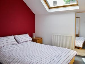 a bedroom with a white bed and a red wall at Biggan Mews in York
