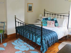 een slaapkamer met een zwart bed met blauwe en roze kussens bij Blacksmiths Cottages in Stiffkey