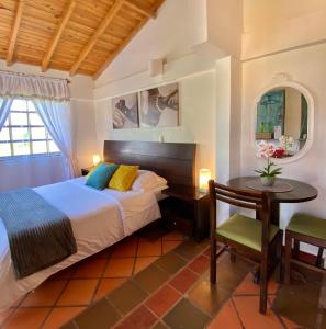 a bedroom with a bed and a desk and a table at Hotel Evoque Sáchica in Villa de Leyva