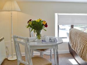 uma mesa de jantar com um vaso de flores em Rosecraddoc Manor - Hayloft em Saint Cleer