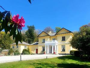 une grande maison jaune avec une grande allée. dans l'établissement Rosecraddoc Manor - Hayloft, à Saint Cleer
