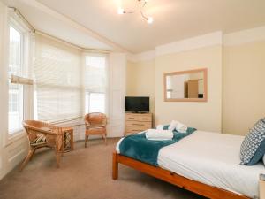 a bedroom with a bed and a tv and a chair at Louisa Cottage in Weymouth