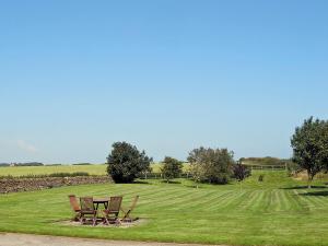 a picnic table and chairs in a field at May Cottage in Hackness