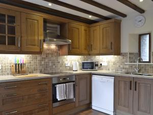 a kitchen with wooden cabinets and white appliances at Rhandir Barn in Ffair-fâch