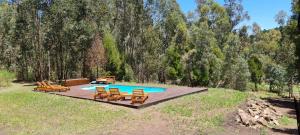 una piscina con sillas y una mesa de picnic en EL BOSQUE DE LAS ANIMAS en Tandil