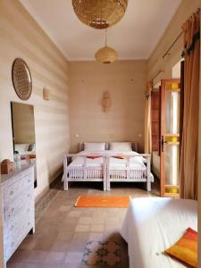a bedroom with two beds and a mirror at DAR MAR'OUKA , Maison d'hôtes in Marrakech