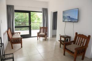 a living room with chairs and a tv on a wall at Departamento con terraza y quincho con asador in Salta