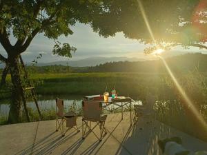 a table and chairs sitting next to a lake at DGD Chiangmai in Mae Rim