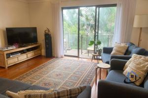 a living room with two blue couches and a television at Harbord House - Ocean views, plunge pool, 2 bed, free-wi-fi, superb location in Freshwater