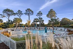 a pool at a resort with white chairs and trees at Ocean Dunes Villas Coligny Beach 43 S Forest Beach Dr, Hilton Head SC #111 Heated Pool Ocean View By Vacation Rental HHI LLC in Hilton Head Island