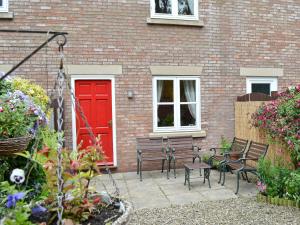 a brick house with a red door and benches at Middle Cottage in Thirsk