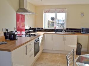 a kitchen with white cabinets and a sink and a window at A Bit On The Side in Chillenden