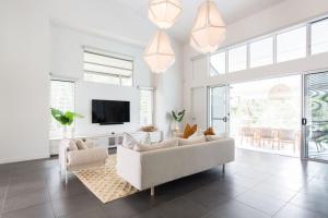 ヌーサヘッズにあるMamilla Beach House Designer Beach Houseの白いソファとテレビのあるリビングルーム