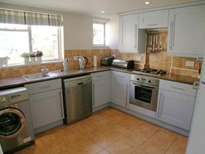 una cocina con armarios blancos y electrodomésticos de acero inoxidable en Waters Edge en Instow