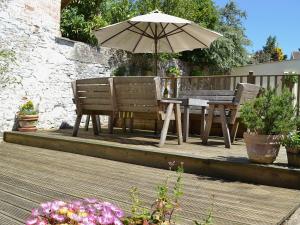 una terraza de madera con mesa y sombrilla en Waters Edge en Instow