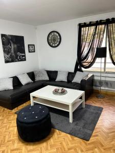 Chez mimi في تولوز: غرفة معيشة مع أريكة سوداء وطاولة قهوة بيضاء