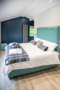 a bedroom with a large bed with a blue headboard at Letham Feus Lodge and Caravan Park in Fife