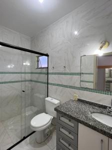 a bathroom with a toilet and a shower and a sink at Dax Bombinhas in Bombinhas