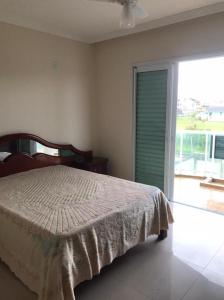 - une chambre avec un lit et une grande fenêtre dans l'établissement Sobrado para locação diaria a poucos metros do mar, à Guaratuba