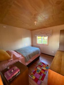 a small bedroom with a bed and a table at Cabaña en La Poza in Hualaihué