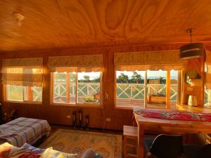 a bedroom with two beds and a table and windows at Cabaña en La Poza in Hualaihué