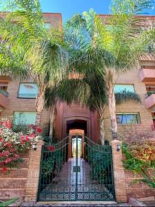 a house with palm trees in front of a door at Apartments Babylone 2 Marrakech in Marrakesh