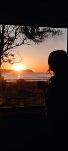 una mujer está mirando hacia la puesta de sol en Cabaña en playa San Ignacio, en Valdivia