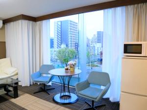 a room with a table and chairs and a large window at Sakuragawa River Side Hotel in Osaka