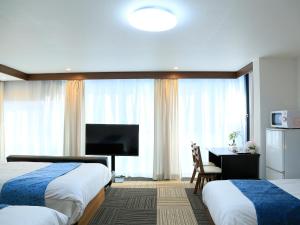 a hotel room with two beds and a desk and a television at Sakuragawa River Side Hotel in Osaka