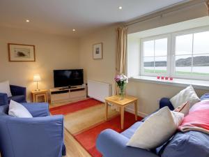 a living room with blue chairs and a tv at Peregrine Cottage in Cambusbarron