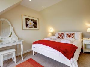 a bedroom with a bed with a mirror and a dresser at Peregrine Cottage in Cambusbarron