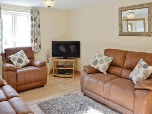 a living room with two leather couches and a television at Hen Ysgubor - 29518 in Fairbourne