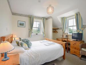 a bedroom with a bed and a desk and a television at Fernlea in Langton Matravers